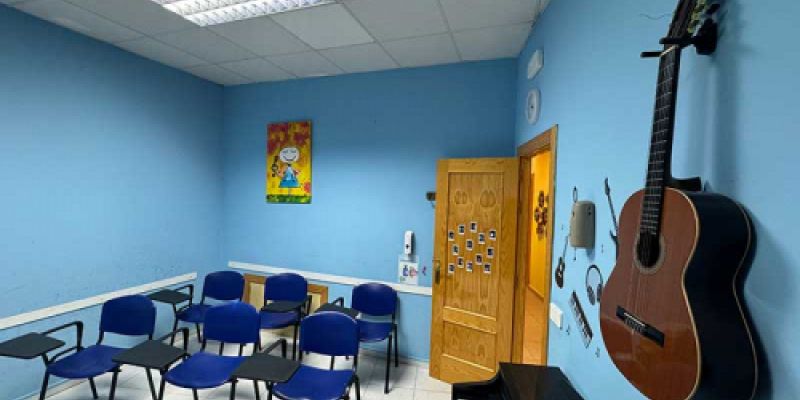 Aula azul con sillas, guitarra y piano para clases